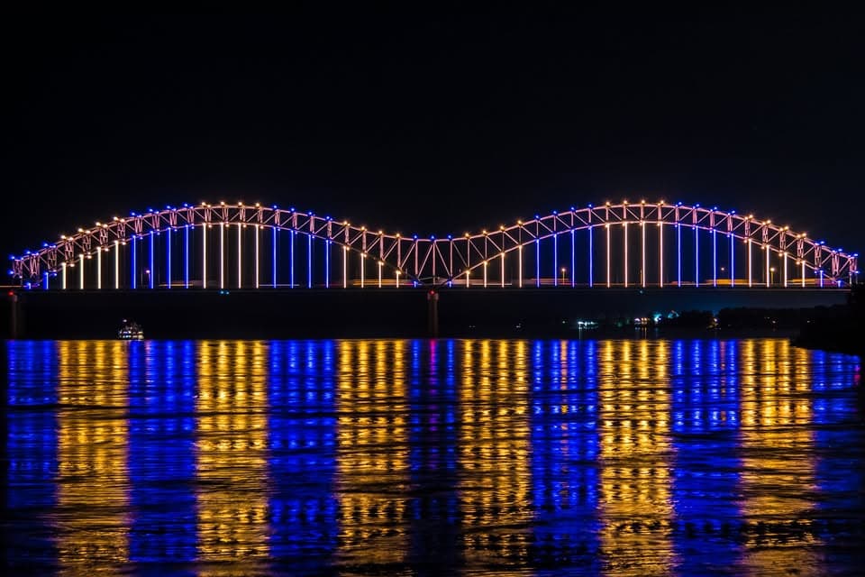 Hernando de Soto Bridge in Memphis at night, blue and gold lights reflected on the Mississippi River